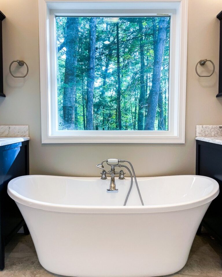 White freestanding tub with a floor mounted filler below a large window, primary bathroom remodel in Winchester, VA