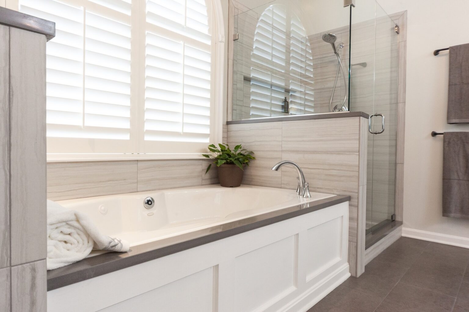 Bathroom remodel with a drop in soaking tub under plantation shutters beside a glass shower in Winchester, VA