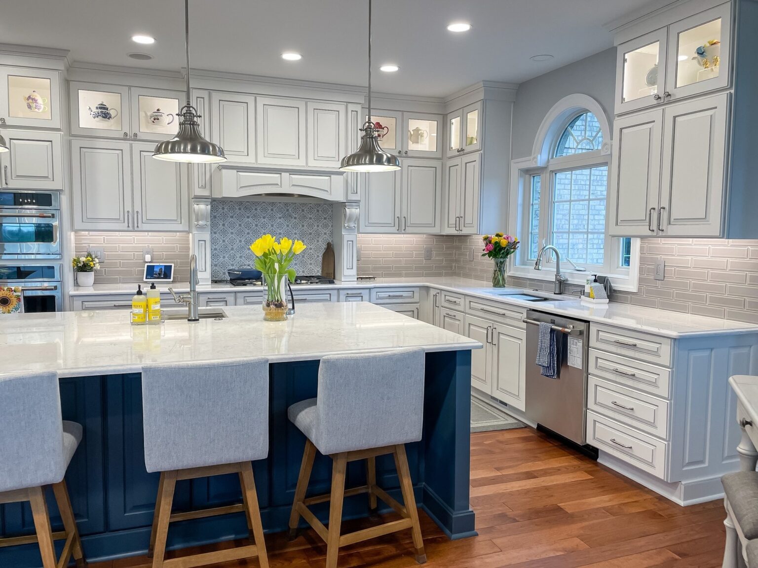 Kitchen remodel with a navy island, white cabinets to the ceiling and an arched window in Winchester, VA