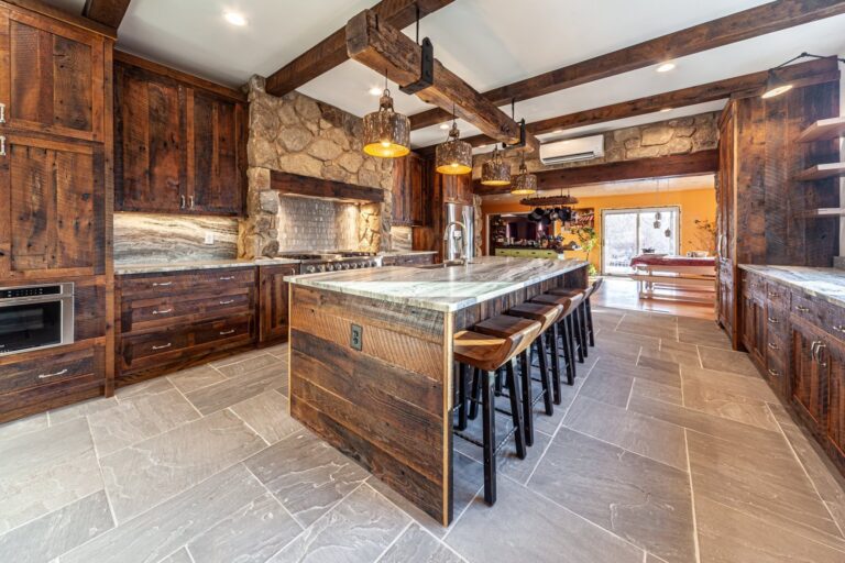 Rustic kitchen remodel with stained wood cabinets, a stone range wall and a long island with bar seating in Winchester, VA